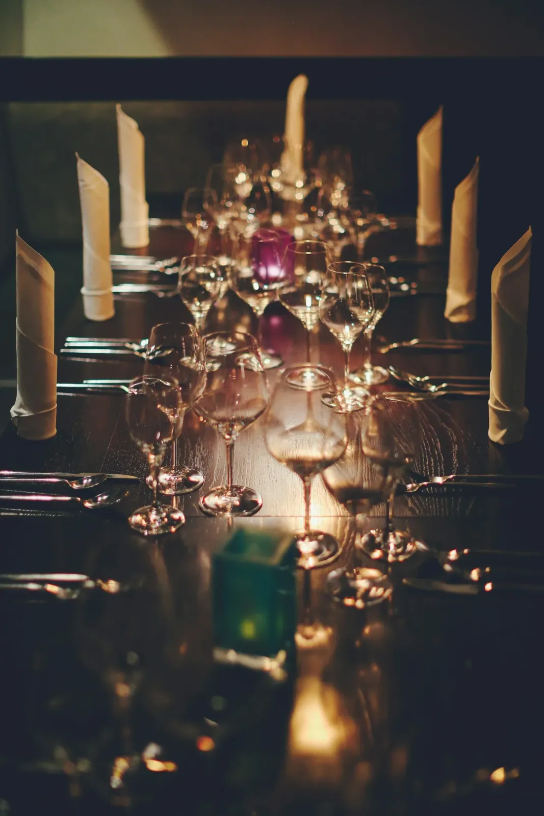 Wine glasses, cutlery, and candlelight on a restaurant table.
